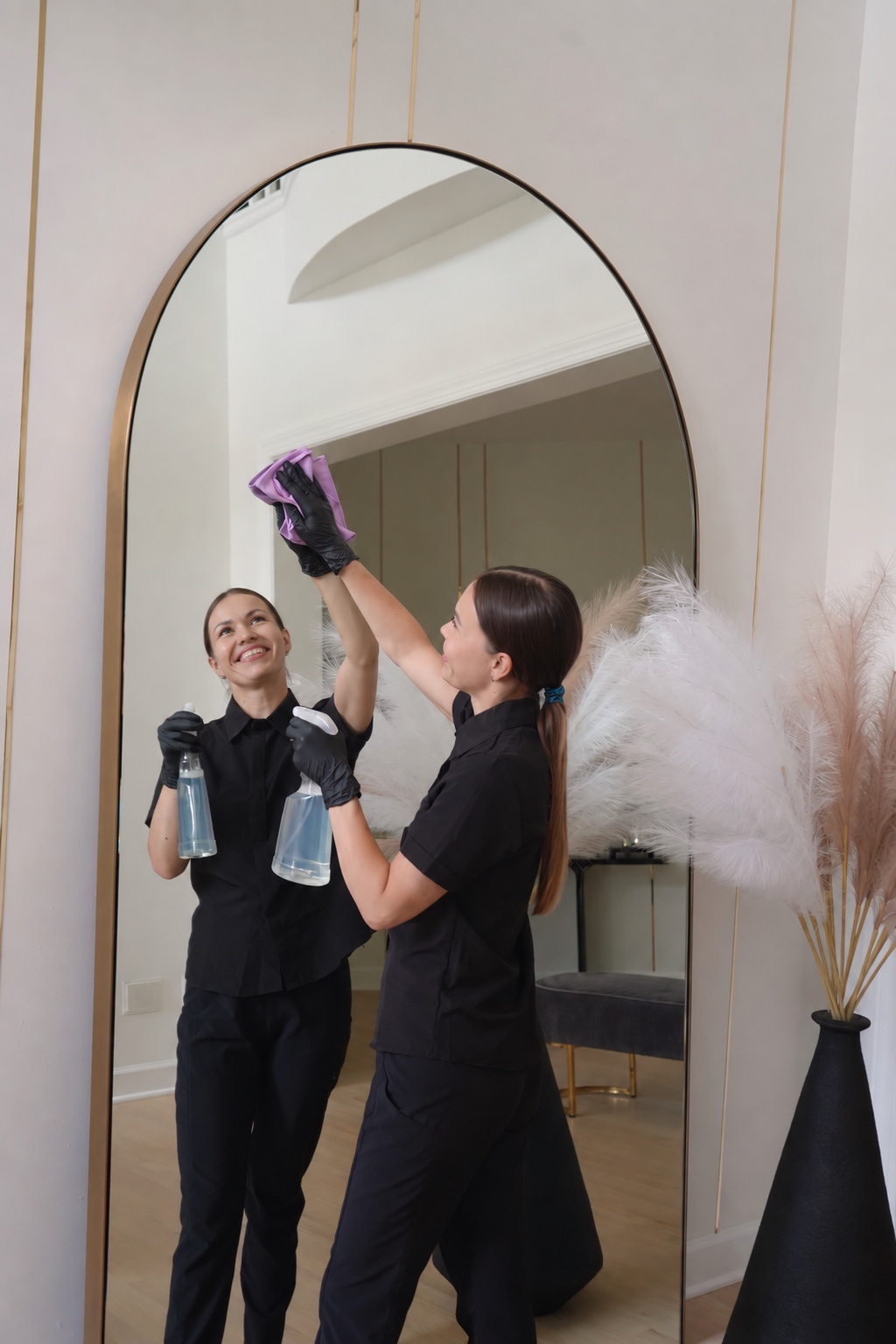 A BroomStar cleaner polishing a full-height arched mirror in a Northern Virginia home